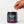 A hand holding a white scoop above a black tub of iAMINOS Brain Health+ dietary supplement powder on a clean white background.