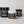 Three supplement containers from iAMINOS on a light gray studio background: a large black Athlete Pro+ tub, a smaller black Brain Health+ tub, and a white Hydrate+ tub in the foreground.